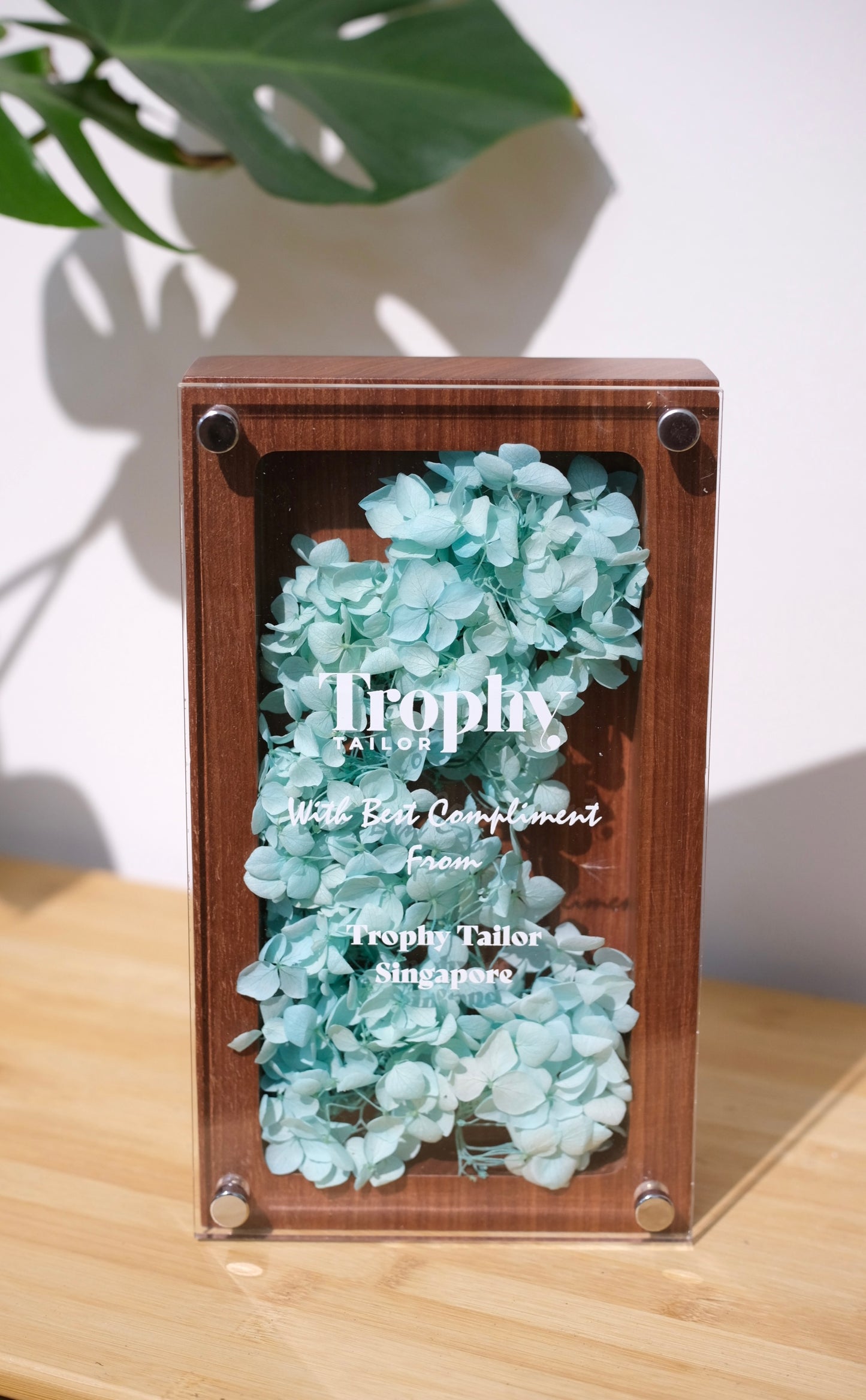 Decorative box with turquoise flowers labeled 'Trophy' on a wooden surface.