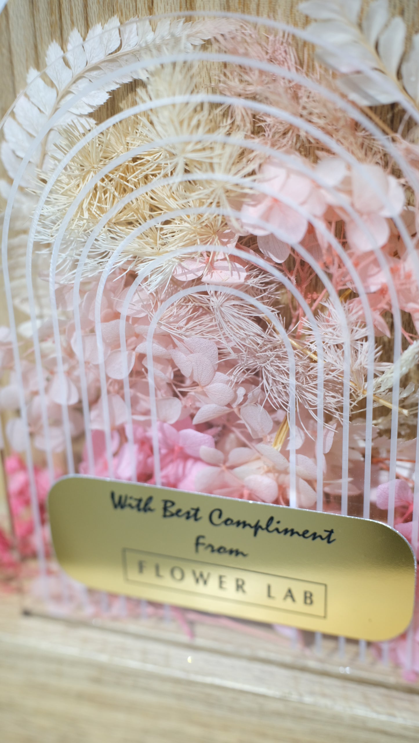 Decorative preserved floral trophy with a gold tag on a textured background