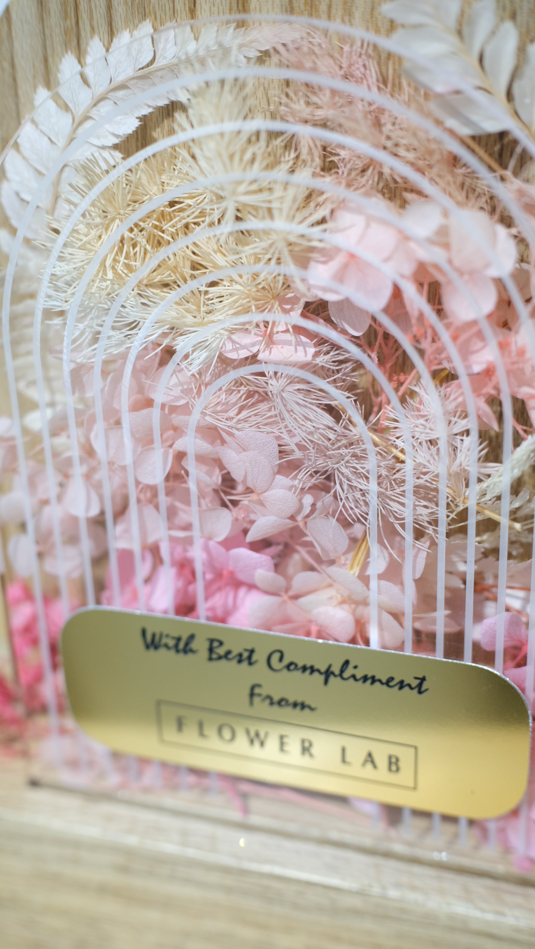 Decorative preserved floral trophy with a gold tag on a textured background
